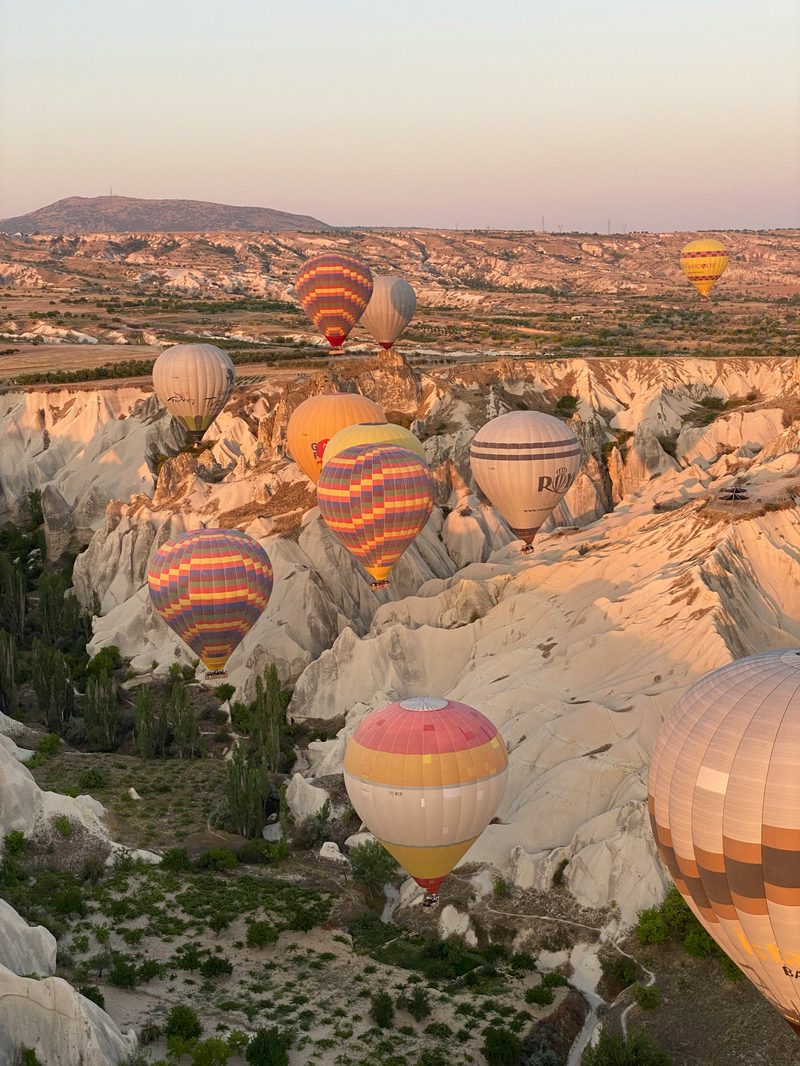 Hot air balloons over Cappadocia fairy chimneys at sunrise
