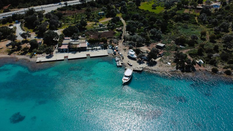 Aerial view of turquoise Turkish coast with boats and olive groves