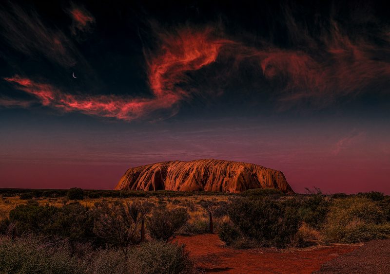 Uluru at sunset under dramatic red sky in the Australian Outback