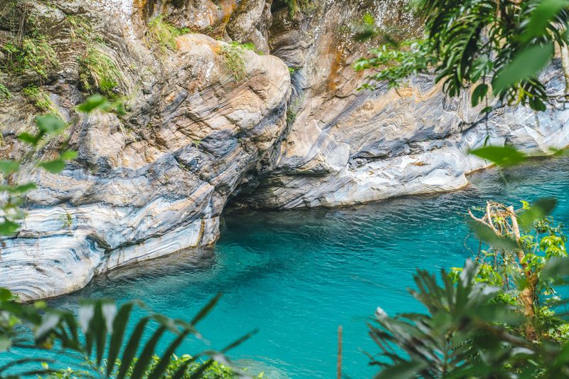 Turquoise water of Taroko Gorge with marble rock walls and tropical foliage
