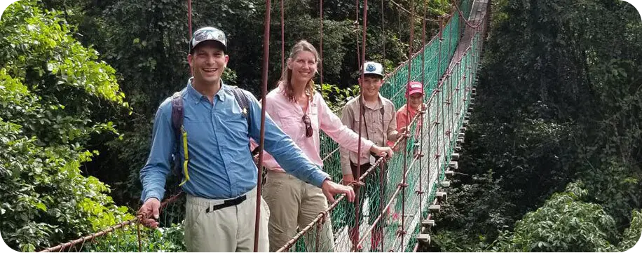 4 people smiling at the camera in a long hanging bridge. The woman in the image is Julie Getzel.