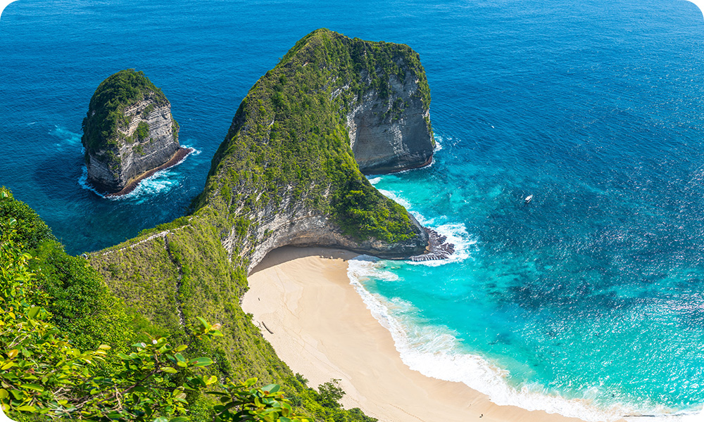 kelingking beach. Aereal view of intricate island rocky formations covered in greens. There is also a beach with multiple colors of turquoise water.