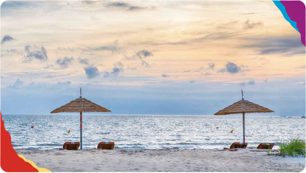 white sand beach with two shade umbrellas in the background overlooking a calm sea.