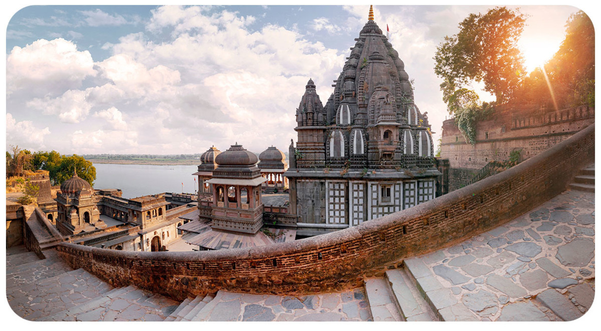 view of elaborate building. There are steps in the foreground and they are made with stones. Lake, Sea or ocean in the baground.