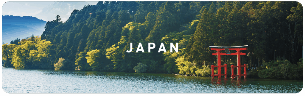 Red torii gate by a lake surrounded by green forest in Japan