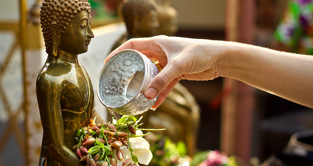 Hand watering Buddha statue.